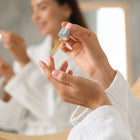 A young woman applying bronzing drops to her hand