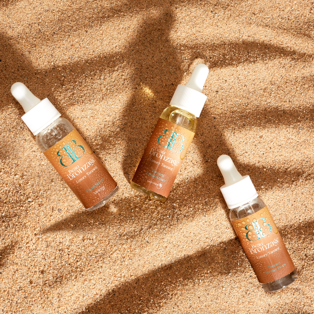 Beau Bronzage Tanning Serum and Drops Trio photographed against a sand dune background